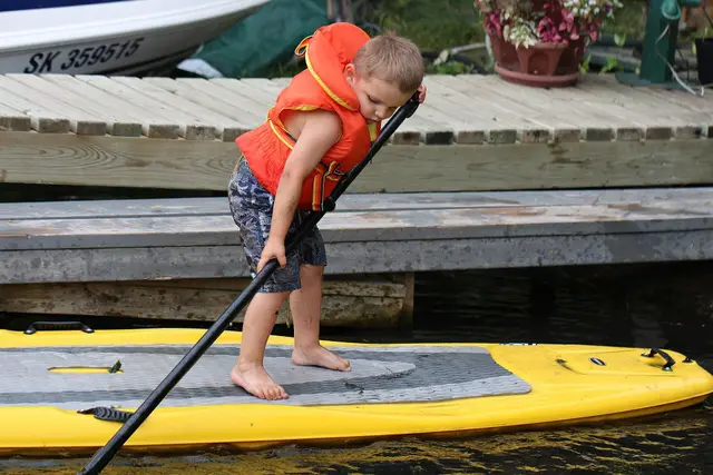 Child paddle boarding at a dock